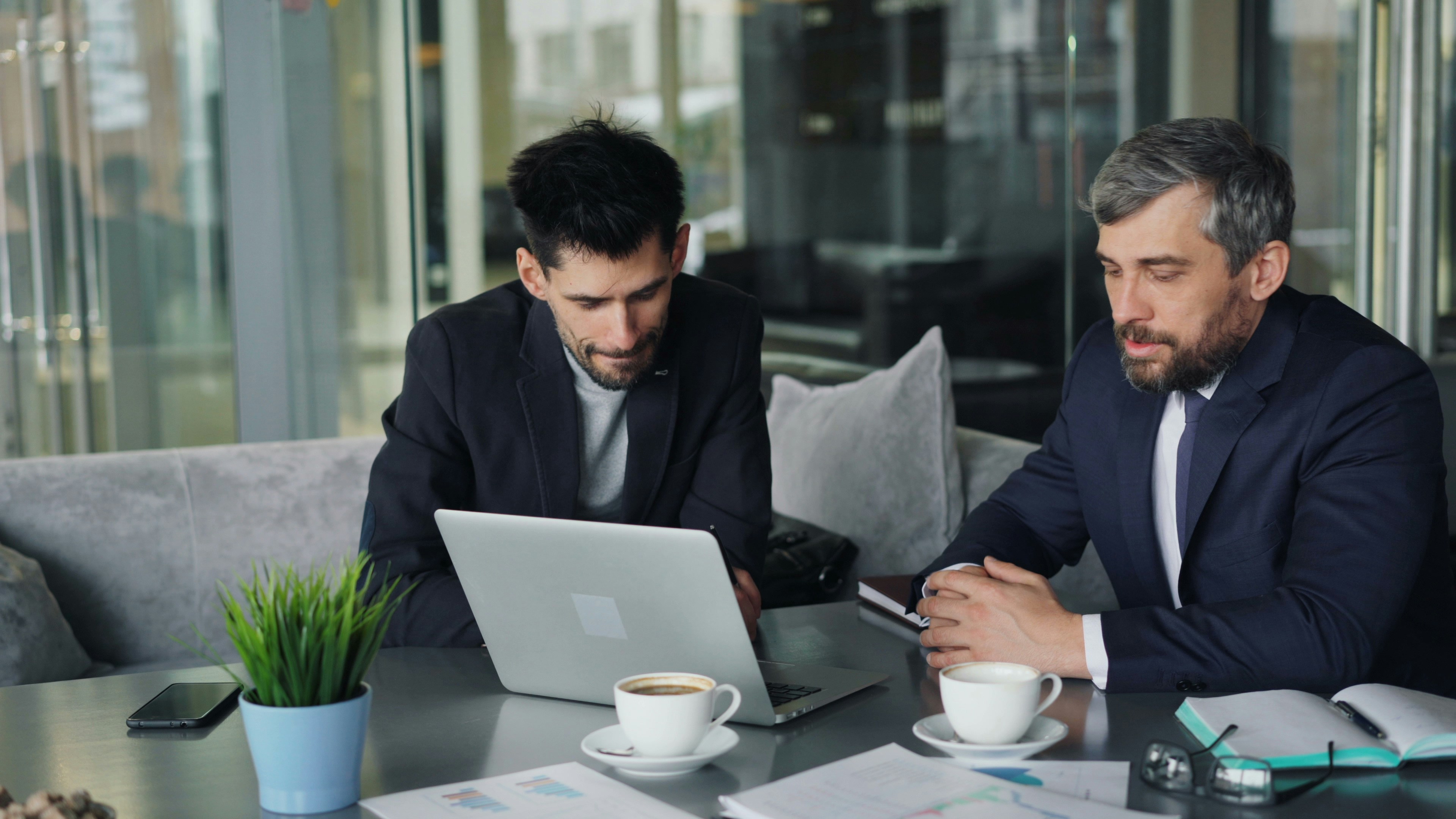 Two team members working together on a laptop - a woman and a man with glasses smiling in a professional office setting